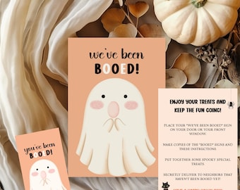 May include: Halloween-themed cards with a ghost illustration and the text "we've been BOOED!" and "you've been BOOED!" A larger card includes instructions: "Enjoy your treats and keep the fun going!" and "Have a Happy Halloween!"
