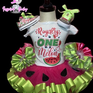 Pu&ograve; includere: Un outfit per bambina con tema anguria con una maglietta bianca che dice "Royalty is One in a Melon" e un tut&ugrave; rosa con dettagli di nastro verde. L'outfit include anche un paio di scarpe da ginnastica a tema anguria.
