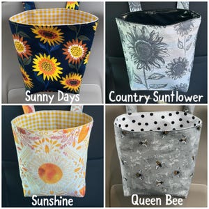 May include: Four fabric car trash bags with different patterns. One bag has sunflowers on a navy background, another has gray sunflowers, a third has a large sunflower design, and the last has bees. Each bag has a contrasting interior and hanging straps.
