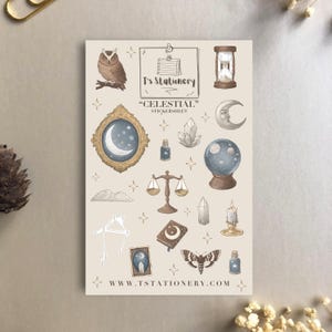 Puede incluir: Una hoja de pegatinas con tem&aacute;tica celestial, con ilustraciones de un b&uacute;ho, un reloj de arena, una luna, una bola de cristal, una balanza y una polilla. Tambi&eacute;n est&aacute; presente el texto "Celestial" y "T's Stationery". El sitio web www.tstationery.com est&aacute; en la parte inferior.