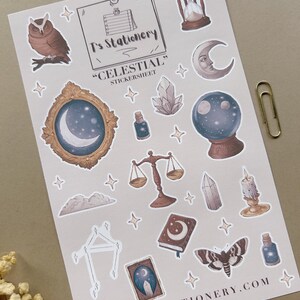 Puede incluir: Una hoja de pegatinas con ilustraciones de tem&aacute;tica celestial. Incluye un b&uacute;ho, un reloj de arena, una luna creciente, una bola de cristal, una balanza y una polilla. Tambi&eacute;n se ve el texto "T's Stationery", "Celestial" y www.tstationery.com.