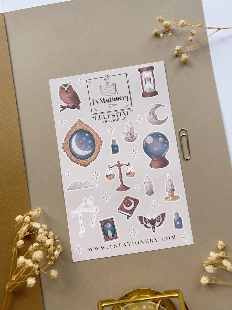 Puede incluir: Una hoja de pegatinas con ilustraciones de tem&aacute;tica celestial. Los dise&ntilde;os incluyen un b&uacute;ho, un reloj de arena, una luna, un cristal, una balanza y una polilla. Tambi&eacute;n aparece el texto "T's Stationery" y "Celestial".