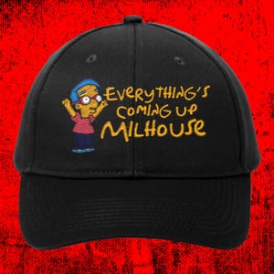 May include: Black baseball cap featuring an embroidered image of Milhouse from The Simpsons. The cap has the phrase "Everything's Coming Up Milhouse" in yellow lettering. The cartoon character is wearing glasses, a pink shirt, and blue shorts.