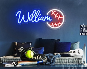 Könnte beinhalten: Neonschild mit dem Namen "William" in blauer Schrift und einem Baseball-Design mit roten Nähten. Das Schild ist an einer dunkelblauen Wand befestigt. Ein Baseballhandschuh, ein Ball und ein Schläger befinden sich auf einem Regal darunter. Dekoration.