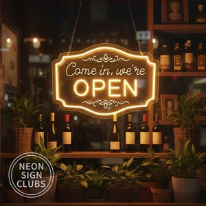 Könnte beinhalten: Ein Leuchtschild in einem Schaufenster zeigt "Come in, we're OPEN". Das Schild ist von einem warmen gelben Schein umgeben und hängt vor Regalen mit Weinflaschen und Topfpflanzen. Das Logo des Geschäfts, "Neon Sign Clubs", ist sichtbar.