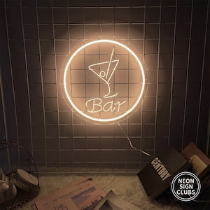 May include: A glowing neon sign with a cocktail glass design inside a circle, with the word "Bar" underneath. The sign is lit with a warm, inviting light and is mounted on a dark, tiled wall. The sign is from Neon Sign Clubs.