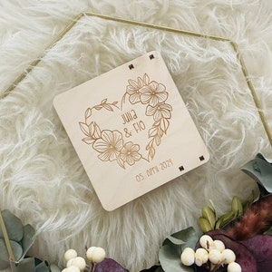 May include: A wooden sign with a floral heart design and the text "Julia & Fio 05. APR 2024".