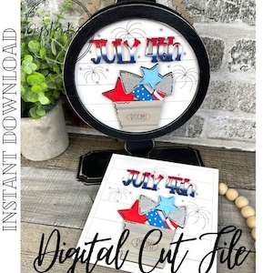 May include: A digital cut file for a July 4th sign featuring a red, white, and blue star, a bucket with the word "BOOM!" on it, and the text "JULY 4th".