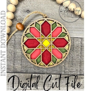 May include: A red, green, and yellow geometric wooden ornament with a stained glass design. The ornament is round and has a hole at the top for hanging. The text "Oyster Bay Design Co." is visible in the background.