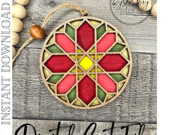 May include: A red, green, and yellow geometric wooden ornament with a stained glass design. The ornament is round and has a hole at the top for hanging. The text "Oyster Bay Design Co." is visible in the background.