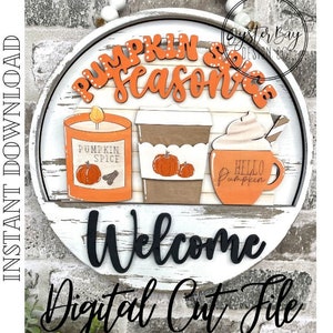 May include: A white round wooden sign with the words "Pumpkin Spice Season" in orange and white lettering. The sign also features a candle, a coffee cup, and the word "Welcome" in black lettering.