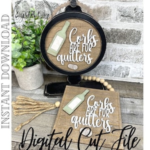 Puede incluir: Un letrero de madera con marco negro y las palabras "Corks are for quitters". El letrero presenta un gráfico de botella de vino verde. También hay un letrero de madera más pequeño con el mismo diseño. La imagen incluye una borla decorativa y una pequeña planta.