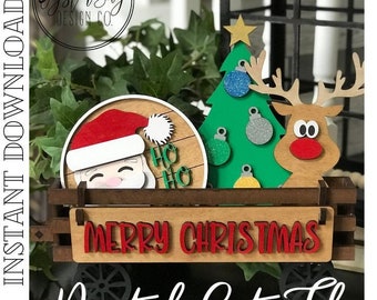 Könnte beinhalten: Eine digitale Schnittdatei für ein Weihnachts-Holzhandwerksprojekt. Das Design zeigt einen Weihnachtsmannkopf, einen Weihnachtsbaum mit Ornamenten, ein Rentier und ein Schild mit der Aufschrift "Frohe Weihnachten".