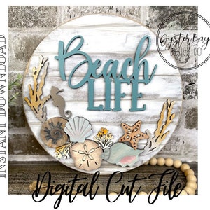 May include: A round wooden sign with the words "Beach Life" in teal blue lettering. The sign is decorated with seashells, starfish, and seaweed.