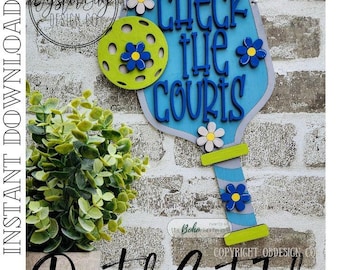 May include: A wooden pickleball paddle-shaped sign with the text "CHECK THE COURTS" in blue. The sign features a green pickleball and blue and white flowers. The words "INSTANT DOWNLOAD" and "Digital Cut File" are also visible.