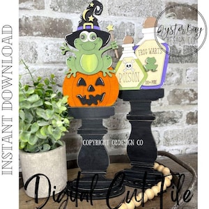 May include: Halloween-themed wooden cutouts. A frog wearing a witch hat sits atop an orange jack-o'-lantern. Beside it are two potion bottles with the words "POISON" and "FROG WARTS". The cutouts are on black pedestals. The words "Digital Cut File" are at the bottom.