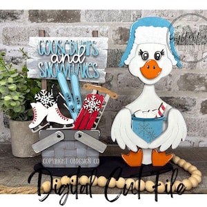 May include: A wooden winter-themed decoration featuring a goose wearing a blue hat and holding a mug of hot cocoa. A basket with skis, ice skates, and a sled sits next to a sign that reads "Goosebumps and Snowflakes".