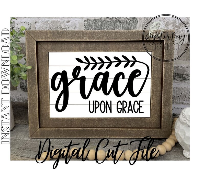 Pu&ograve; includere: Un cartello in legno incorniciato con il testo "grace upon grace" in corsivo nero con un piccolo disegno di ramo con foglie sopra la parola "grace".