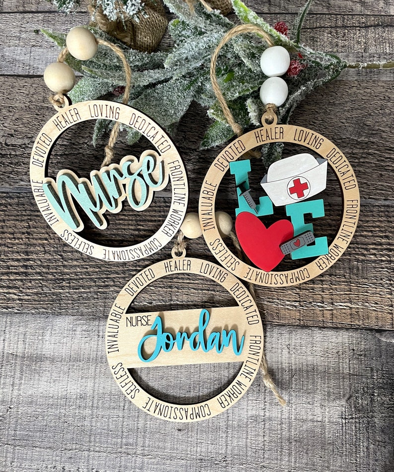 Pu&ograve; includere: Tre ornamenti in legno con la parola "Infermiera" e le parole "Compassionevole, Altruistico, Inestimabile, Devoto, Guaritore, Amorevole, Dedicato, Lavoratore in prima linea" attorno al cerchio. Un ornamento ha un cuore rosso con una benda e una siringa. Un ornamento ha il nome "Jordan".
