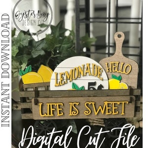 May include: A wooden wagon with wheels, decorated with lemons, greenery, and signs that read "Lemonade 5¢" and "Hello". The wagon also has a sign that says "Life is Sweet".