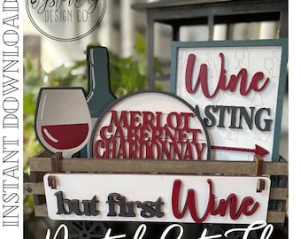 May include: A wooden sign with the text "but first wine" in red and black lettering. The sign is in a wooden wagon with wheels. There are other signs in the background with the words "wine tasting", "merlot", "cabernet", and "chardonnay".