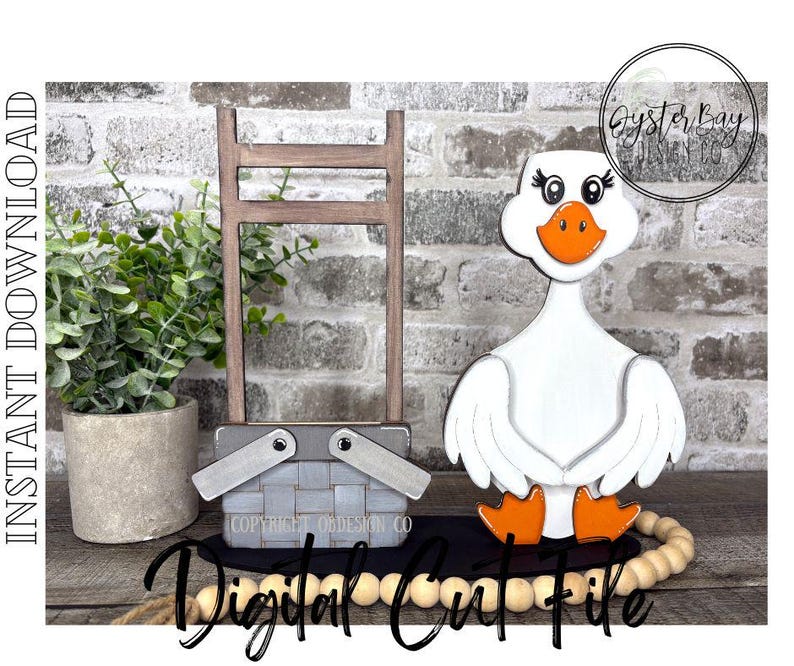 May include: A wooden goose figurine with an orange beak and feet, a picnic basket, and a small ladder are displayed on a black tray with wooden beads. A potted plant is to the left. The words "Digital Cut File" are written in cursive.