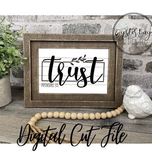 May include: A digital cut file design featuring the word "trust" in a cursive font with a small branch of leaves above the word. The design is framed in a rustic wooden frame and has the text "Proverbs 3:5" below the word "trust".