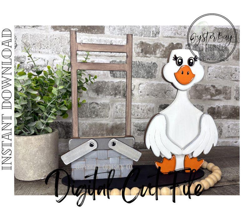 May include: A wooden goose figurine with orange feet and beak, white body, and a smiling face. A gray picnic basket and a wooden ladder are also present. The words "Digital Craft File" are written in cursive.