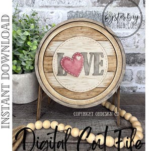 May include: Wooden round sign with a light brown frame and a light wood grain center. The sign features the word "LOVE" with a pink heart. The sign is on a wooden stand with a string of wooden beads in front.