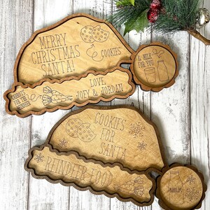 May include: Wooden Christmas Eve tray set with a Santa hat design. The tray has sections for cookies, milk, carrots, and a note for Santa. The text on the tray reads "Merry Christmas Santa!" "Cookies for Santa" "Reindeer Food" "Carrots for the Reindeer" "Love Joey & Jordan" "& Milk for You".