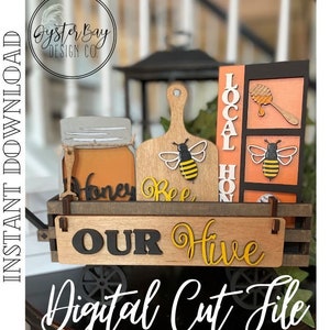 Puede incluir: Un carro de madera con un letrero que dice "Our Hive" y que presenta un tarro de miel, un recorte de abeja y un letrero que dice "Local Honey".