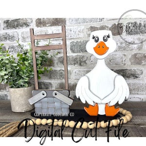 May include: A wooden goose figurine with orange feet and beak, white body, and black eyes. A gray picnic basket, a small wooden ladder, and a potted plant are also present. The words "Instant Download" and "Digital Cut File" are visible.