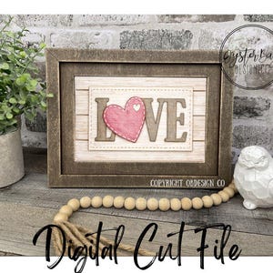 May include: A framed wooden sign with the word "LOVE" and a pink heart. The sign is on a wooden surface with a string of wooden beads and a decorative bird. The words "INSTANT DOWNLOAD" and "Digital Cut File" are also visible.