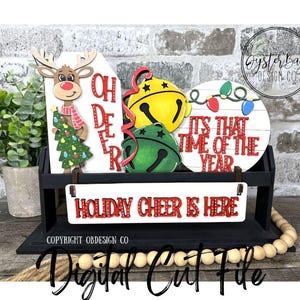 May include: A black wooden Christmas decoration with three signs. One sign says "OH DEER" with a reindeer holding a Christmas tree. Another says "IT'S THAT TIME OF THE YEAR". The third sign says "HOLIDAY CHEER IS HERE".