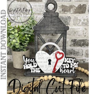 May include: A gray wooden lantern with a heart-shaped lock and key design. The heart has the words "I love you" and "Key to my heart." The key is red. The words "You hold the key" are also present.