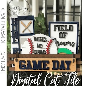May include: A wooden wagon with a blue and white sign that says "GAME DAY". The wagon is filled with baseball-themed decorations, including a sign that says "FIELD OF DREAMS", a sign that says "HOME", and a baseball with the text "THERE'S NO CRYING".