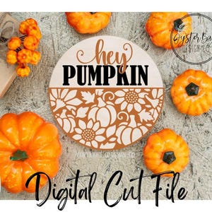 K&ouml;nnte beinhalten: Ein runder Holzschild mit den Worten "hey PUMPKIN" und einem floralen und K&uuml;rbis-Design. Das Schild ist von orangefarbenen K&uuml;rbissen und dekorativen Elementen umgeben. Die Worte "Digital Cut File" sind ebenfalls sichtbar.