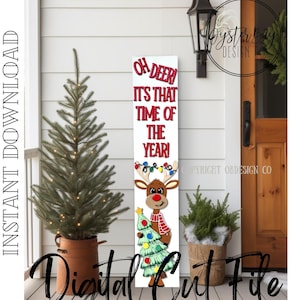 Op de afbeelding: Een wit verticaal bord met de tekst "OH DEER! IT'S THAT TIME OF THE YEAR!" in rode letters. Een cartoon rendier met een rode neus, sjaal en kerstboom staat onderaan. De woorden "INSTANT DOWNLOAD" en "Digital Cut File" zijn ook aanwezig.