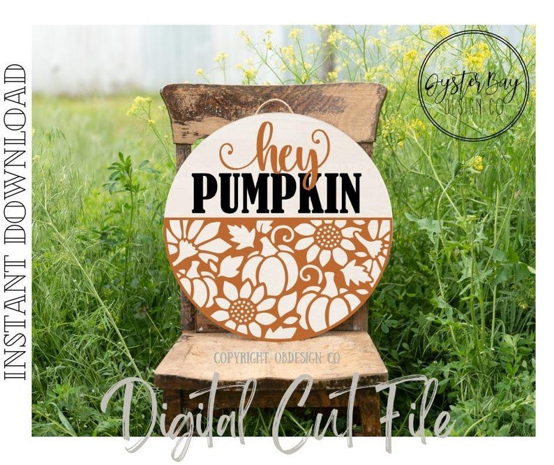 K&ouml;nnte beinhalten: Runder Holzschild mit den Worten "hey PUMPKIN" in Braun und Schwarz. Die untere H&auml;lfte zeigt ein ausgeschnittenes Design aus K&uuml;rbissen und Sonnenblumen in Hellbraun. Das Schild h&auml;ngt an einem Holzstuhl in einem Feld.