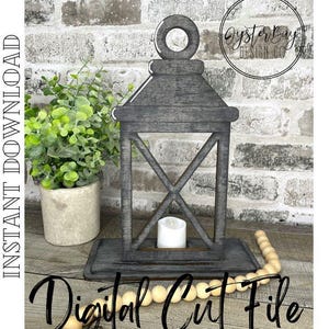 May include: A gray wooden lantern with a decorative handle and a cross-shaped design on the front. The lantern is sitting on a wooden base and has a small white candle inside. The lantern is surrounded by wooden beads.