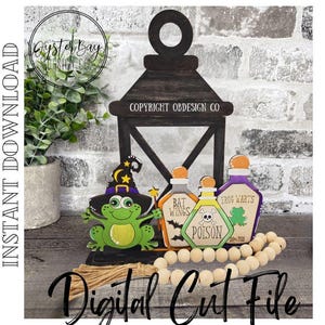 May include: A wooden Halloween-themed lantern with a frog wearing a witch hat, and three potion bottles. The bottles are labeled "Bat Wings", "Poison", and "Frog Warts". A string of wooden beads and the text "Digital Cut File" are also visible.