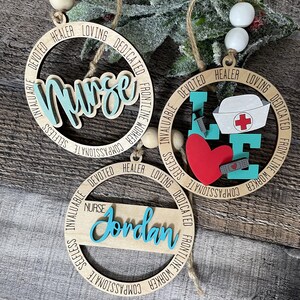 Pu&ograve; includere: Tre ornamenti in legno con un tema infermieristico blu turchese. Gli ornamenti sono rotondi e hanno le parole "Infermiera", "Amore" e "Jordan" scritte su di essi. Gli ornamenti sono decorati con parole come "compassionevole", "altruistico", "inestimabile", "lavoratore in prima linea", "dedicato", "guaritore" e "amorevole".