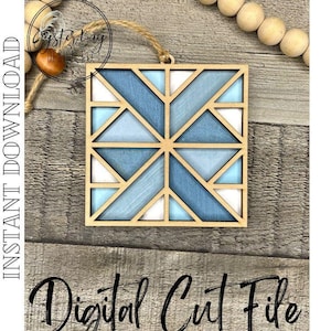 Może przedstawiać: Cyfrowy plik do cięcia dla geometrycznej drewnianej ozdoby w niebiesko-białym schemacie kolorystycznym. Ozdoba ma kształt kwadratu i posiada geometryczny wzór z trójkątów i kwadratów. Ozdoba znajduje się na drewnianym tle.