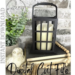 May include: Black wooden lantern with a white candle inside. The lantern has a handle and a grid pattern. The lantern is sitting on a stack of books with a wooden bead garland.