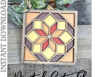 May include: A square, wooden ornament with a geometric design in shades of orange, yellow, and red. The ornament has a starburst pattern in the center and is framed by a light brown border. The text "Digital Cut File" is at the bottom.