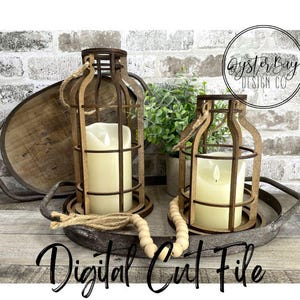 Puede incluir: Dos faroles de velas de madera con un diseño enjaulado, sentados en una bandeja de madera con una guirnalda de cuentas decorativas. Los faroles están iluminados con velas blancas y tienen un estilo rústico, de granja. El texto "Oyster Bay Design Co." es visible en el fondo.