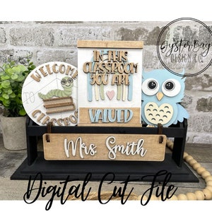 May include: A digital cut file for a classroom decor set. The set includes a welcome to classroom sign with a worm and books, a sign that says "In this classroom you are valued", and a blue owl. The set also includes a sign that says "Mrs. Smith".