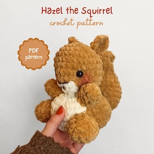 Puede incluir: Un peluche de ardilla tejido a ganchillo en tonos marrón y crema, con una textura suave. La ardilla tiene la barriga blanca, mejillas rosas y ojos negros. El texto en la imagen dice "Hazel the Squirrel crochet pattern" y "PDF pattern".