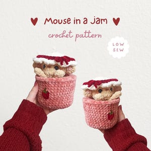 May include: Two crocheted plush mice sitting inside pink textured jam jars, each wearing a white and red hat with a bow. The text reads Mouse in a Jam crochet pattern and LOW SEW. The mice have small dark eyes and light tan yarn bodies.