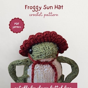 Puede incluir: Un juguete de rana de ganchillo con un sombrero para el sol rojo y una bufanda blanca y roja. La rana tiene la piel verde y un cuerpo de color crema. El texto de la imagen dice "Froggy Sun Hat crochet pattern" y "suitable for classic knitted frog".